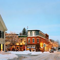 a small town in the winter with snow on the ground and buildings lit up at night