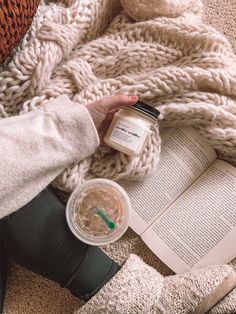 a person sitting on the floor next to an open book and a jar of liquid