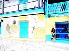 a woman standing in front of a blue and yellow building