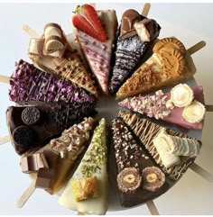 an assortment of desserts arranged in a circle on sticks with chocolate, strawberries and other toppings