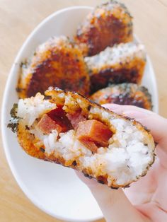 someone is holding up a sushi with rice and bacon on it in their hand