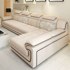 a large white couch sitting in a living room next to a table and pictures on the wall