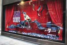 a window display with red curtains and mannequins