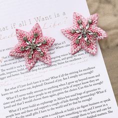 two pink beaded flowers sitting on top of an open book