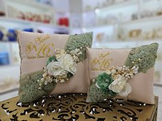 two pillows with flowers on them are sitting on a gold bench in a store aisle