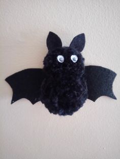 a stuffed bat hanging from the wall with eyes on it's back and wings spread out