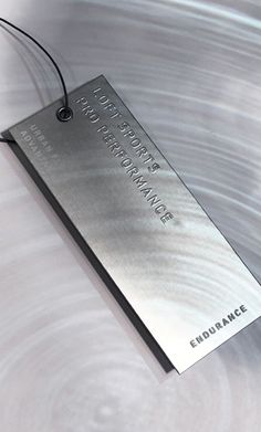 a metal tag with the words embrace on it hanging from a string in front of a shiny surface