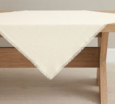 a white table cloth on top of a wooden table with a wood bench in the background