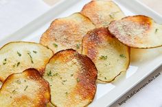 some fried potato wedges on a white plate with parsley sprinkled on top