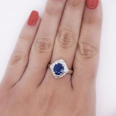 a woman's hand with a blue and white diamond ring on her left hand