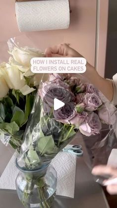 a vase filled with flowers sitting on top of a table next to a roll of toilet paper