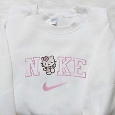 Hello Kitty x Nike Embroidered Shirt: Introducing the perfect blend of cuteness and sportiness with our Hello Kitty x Nike Embroidered Shirt. Made with high-quality fabric, this shirt showcases a unique collaboration between two iconic brands. The intricate embroidery of Hello Kitty and Nike logos adds a touch of playfulness to your wardrobe. With its comfortable fit and stylish design, this shirt is perfect for casual outings or gym sessions. Show off your love for Hello Kitty and Nike with thi Women Nike Sweatshirt, Hello Kitty Nike Sweatshirt, Nike Hello Kitty Sweater, Fall Graphic Sweatshirt, Cute Nike Hoodies, Cute Hoodie With Custom Embroidery And Crew Neck, Cute Custom Embroidered Crew Neck Hoodie, Cute Cotton Sweatshirt With Embroidered Logo, White Hello Kitty Sweatshirt For Streetwear