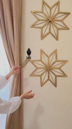 two wooden snowflakes are hanging on the wall next to a window with curtains