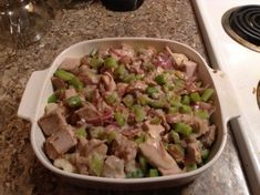 a casserole dish with meat and vegetables in it sitting on the kitchen counter