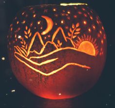 a carved pumpkin sitting on top of a table next to a window with the moon and mountains in it