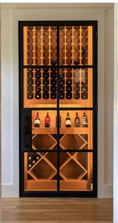 a wine cellar with many bottles in it and lights on the wall behind it, along with hardwood flooring