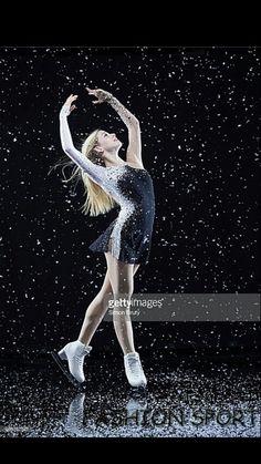 a woman is dancing in the rain with her arms out and legs spread wide as she stands on one leg