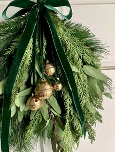 a christmas wreath with bells and greenery hanging on a door handle, ready to be hung