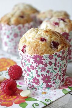 muffins with raspberries and white chocolate chips on a floral table cloth