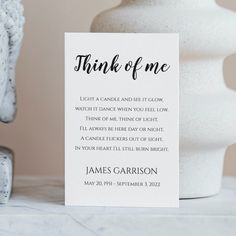 a white vase sitting on top of a table next to a card that says think of me