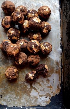 chocolate covered donuts sitting on top of a metal pan next to some rusted paper