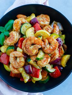 a bowl filled with shrimp and veggies on top of a white table cloth