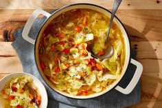 two bowls filled with soup on top of a wooden table next to a spoon and napkin