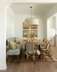 a dining room table with chairs and a bench in the middle of an open floor plan