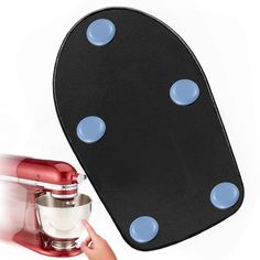 a hand holding a red mixer near a black and white plate with blue dots on it