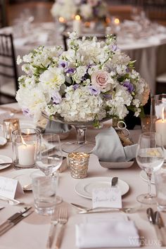 the centerpieces on this table are filled with white and purple flowers