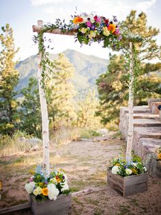 an outdoor ceremony setup with flowers and greenery on the altar, in front of mountains