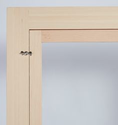 an open wooden door with two knobs on the front and back sides, in a plain light wood frame