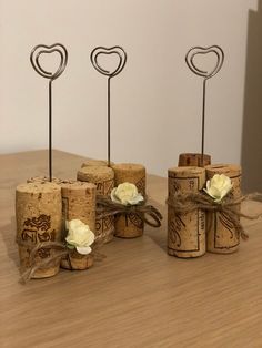 three wine corks with hearts and flowers on them sitting on a wooden table next to each other