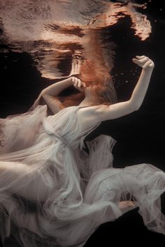 a woman in a white dress floating under water