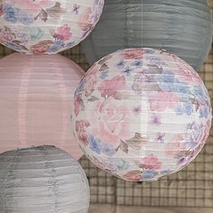 three paper lanterns hanging from the ceiling in front of a wall with flowers on them