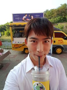 a young man drinking from a straw in front of a food truck