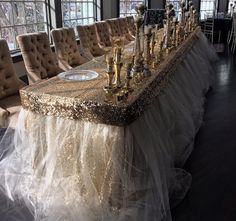 a long table covered in gold and white cloths with candlesticks on it