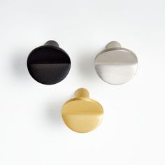 three door knobs in different colors on a white surface with one black, one gold and one silver