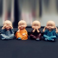 five small buddha figurines sitting in a row on a black surface with blurry background