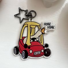 a keychain with a cartoon character driving a red car and the words honk honk honk on it