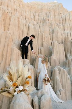 a bride and groom are standing on the rocks in an area that looks like desert