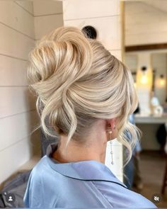 a woman with blonde hair in a low bun hairstyle looking at the side of her head