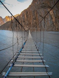 there is a long bridge over the water that leads to some mountains in the distance