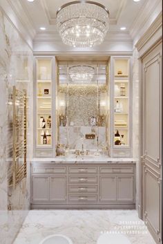 an elegant bathroom with chandelier and marble counter tops, white walls and cabinets