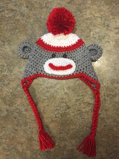 a crocheted monkey hat with a red and white pom - pom