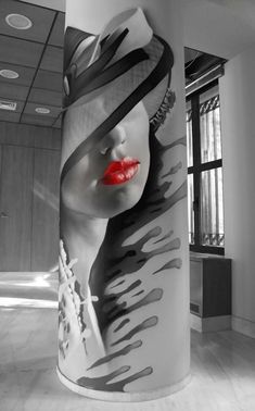 a large white pillar with a woman's face painted on it and red lips