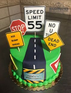 a cake decorated with street signs and road signs on top of the cake is green frosting