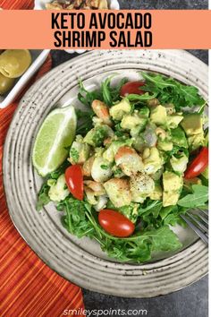 a salad with shrimp, avocado and tomatoes in a bowl next to olives