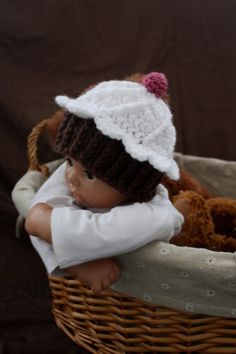 a baby doll sitting in a wicker basket with a teddy bear on it's back