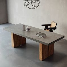 a table with a book on it and a chair next to it in front of a wall